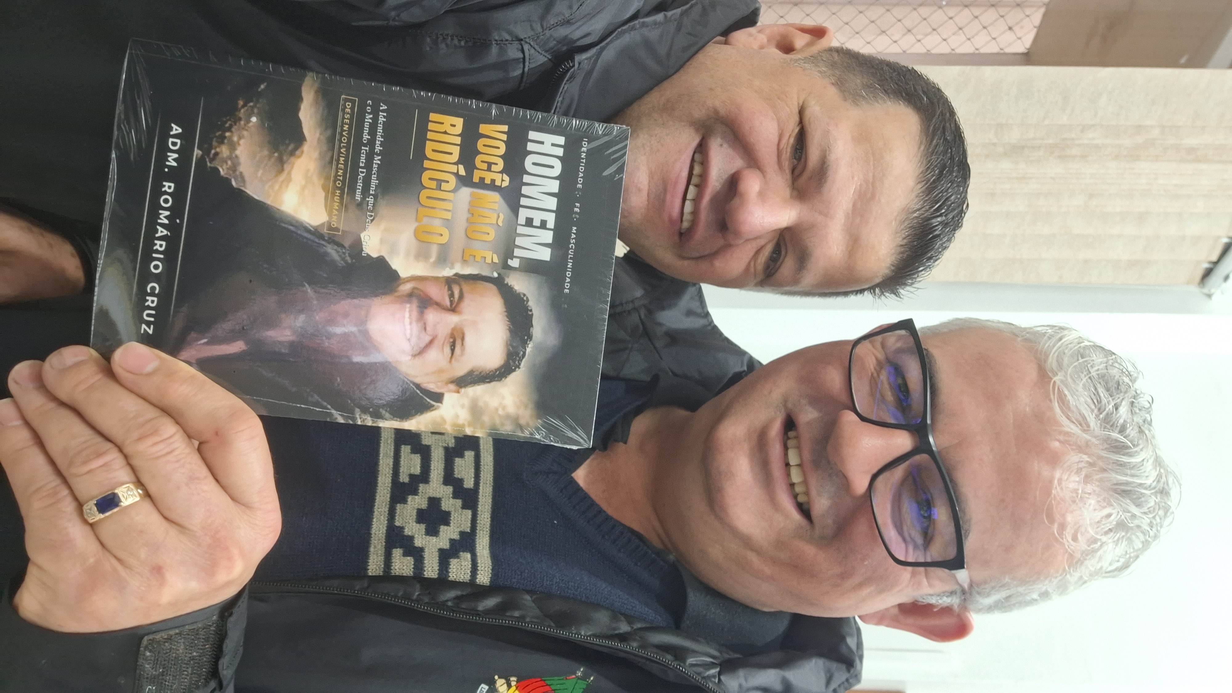 Adm. Romário Cruz com leitor segurando o livro Homem, Você Não É Ridículo