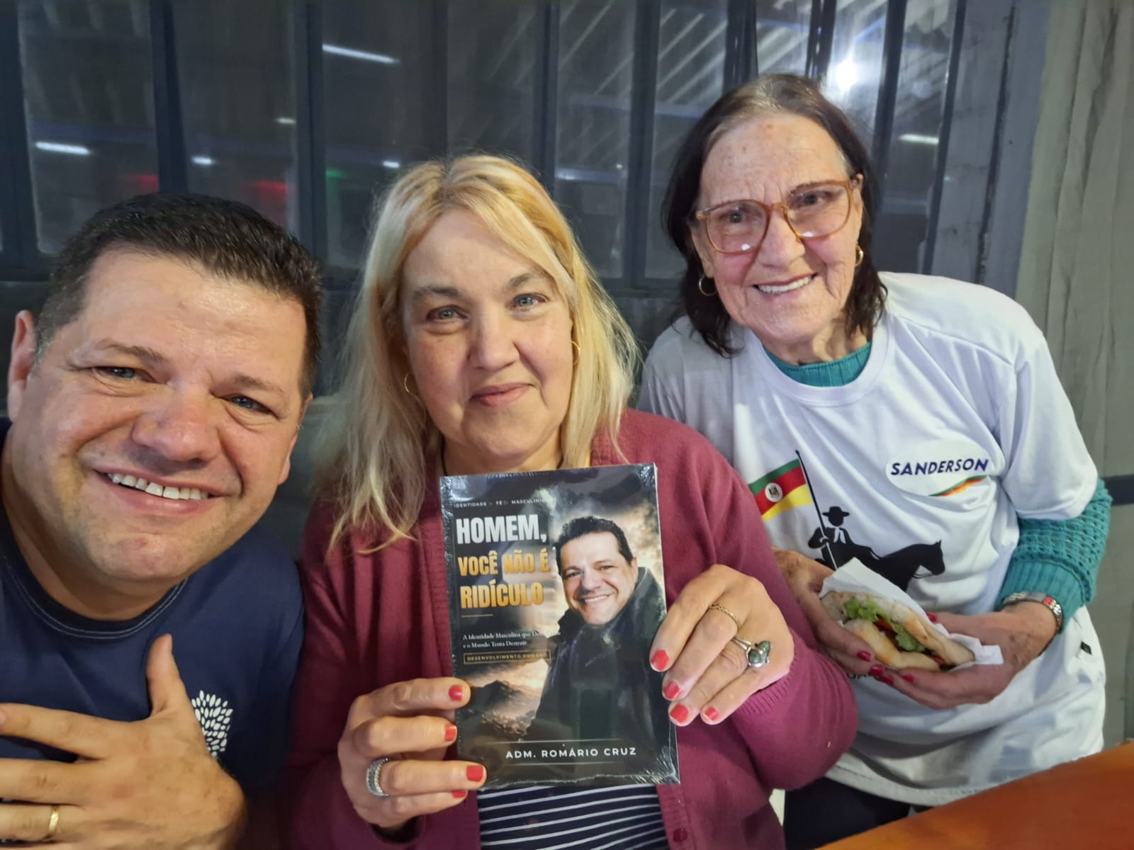 Adm. Romário Cruz com leitor segurando o livro Homem, Você Não É Ridículo