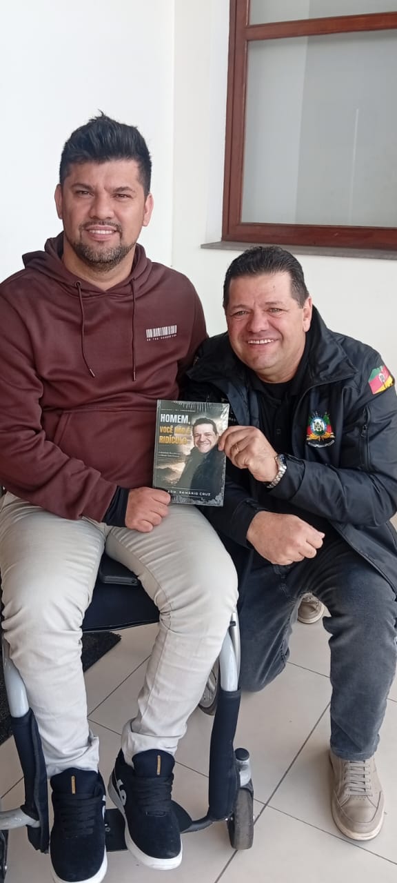 Adm. Romário Cruz com leitor segurando o livro Homem, Você Não É Ridículo