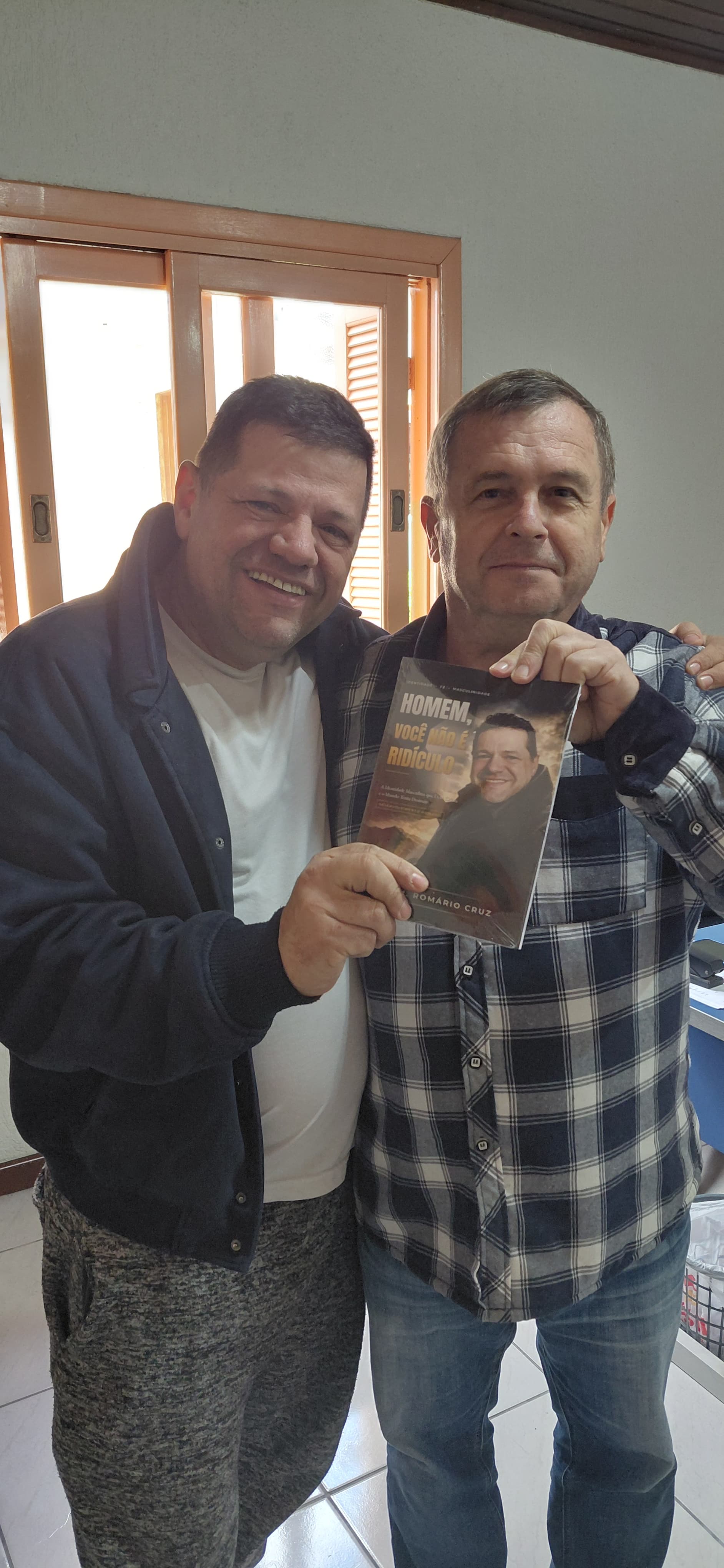 Adm. Romário Cruz com leitor segurando o livro Homem, Você Não É Ridículo