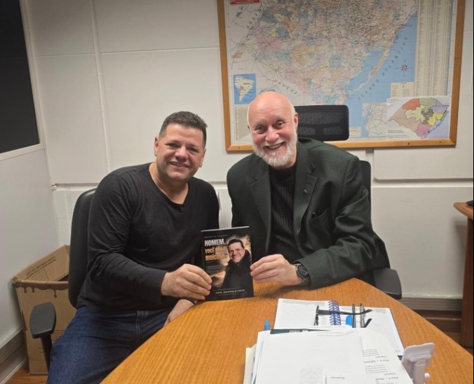 Adm. Romário Cruz com leitor segurando o livro Homem, Você Não É Ridículo