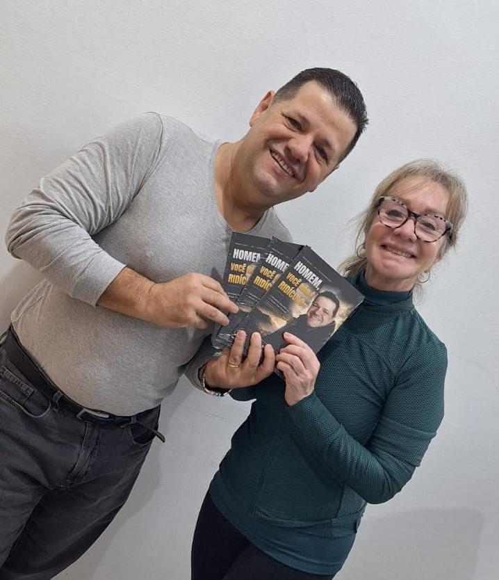 Adm. Romário Cruz com leitor segurando o livro Homem, Você Não É Ridículo