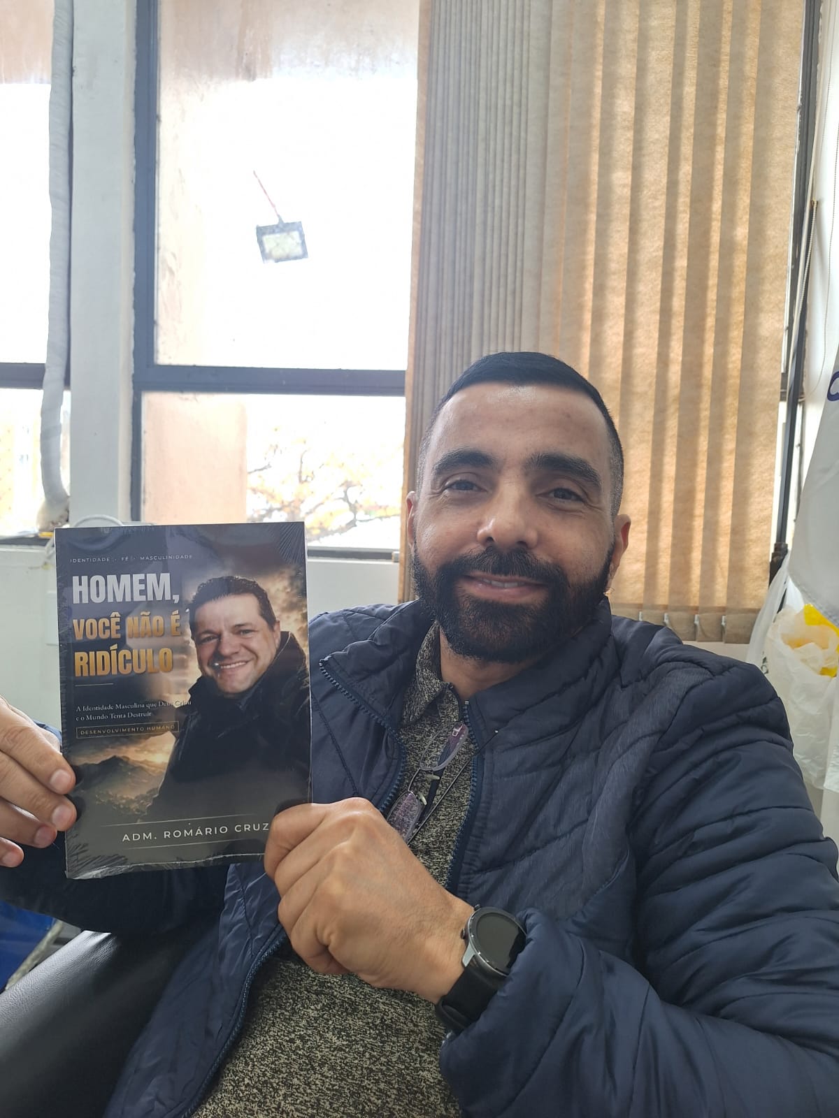 Adm. Romário Cruz com leitor segurando o livro Homem, Você Não É Ridículo