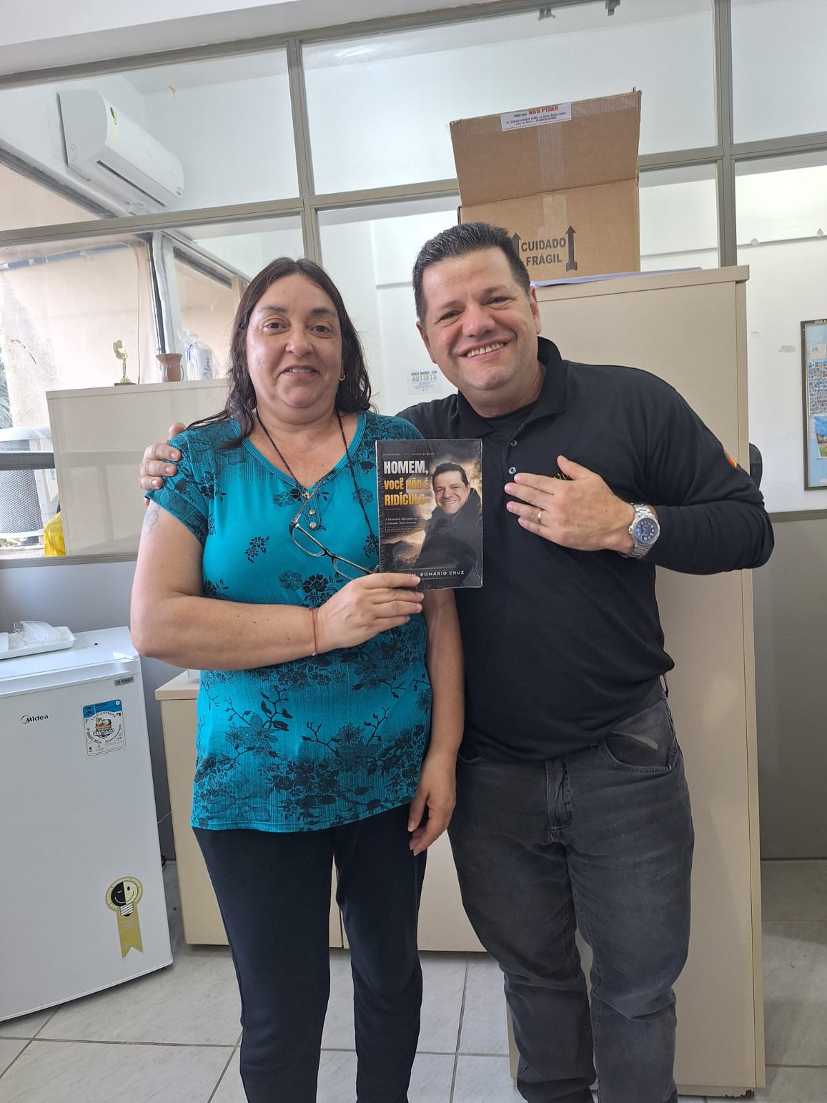 Adm. Romário Cruz com leitor segurando o livro Homem, Você Não É Ridículo