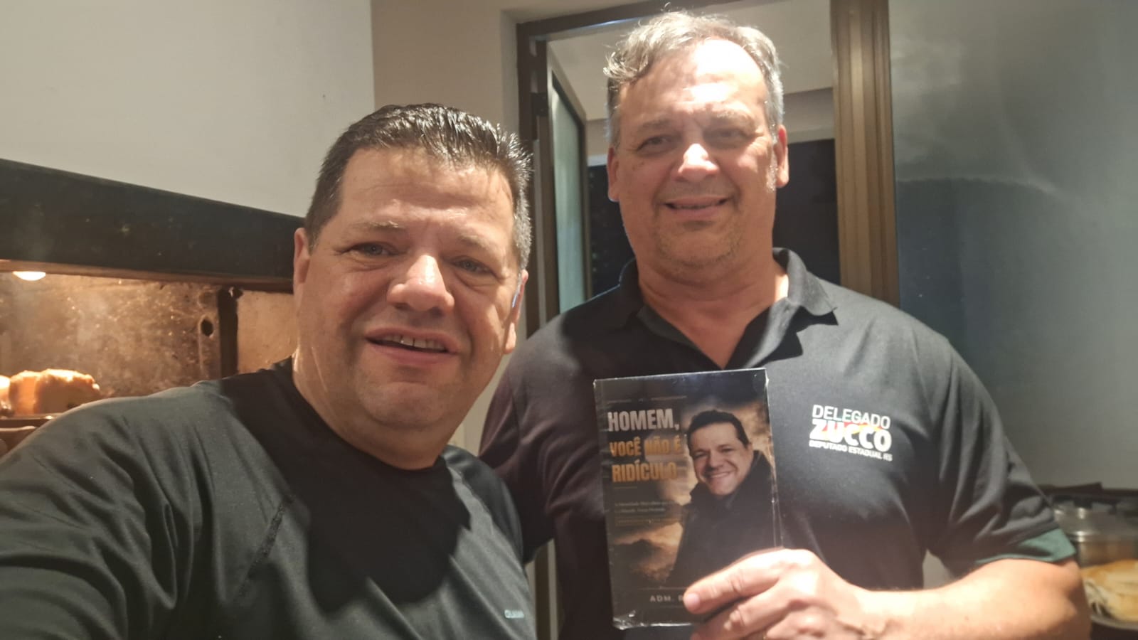 Adm. Romário Cruz com leitor segurando o livro Homem, Você Não É Ridículo