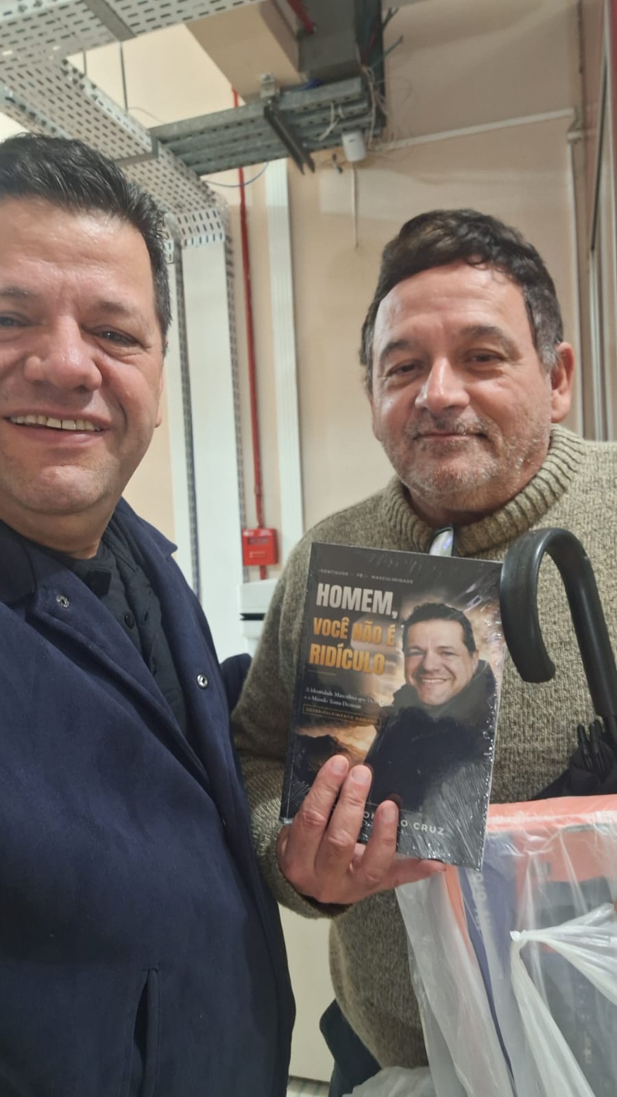Adm. Romário Cruz com leitor segurando o livro Homem, Você Não É Ridículo