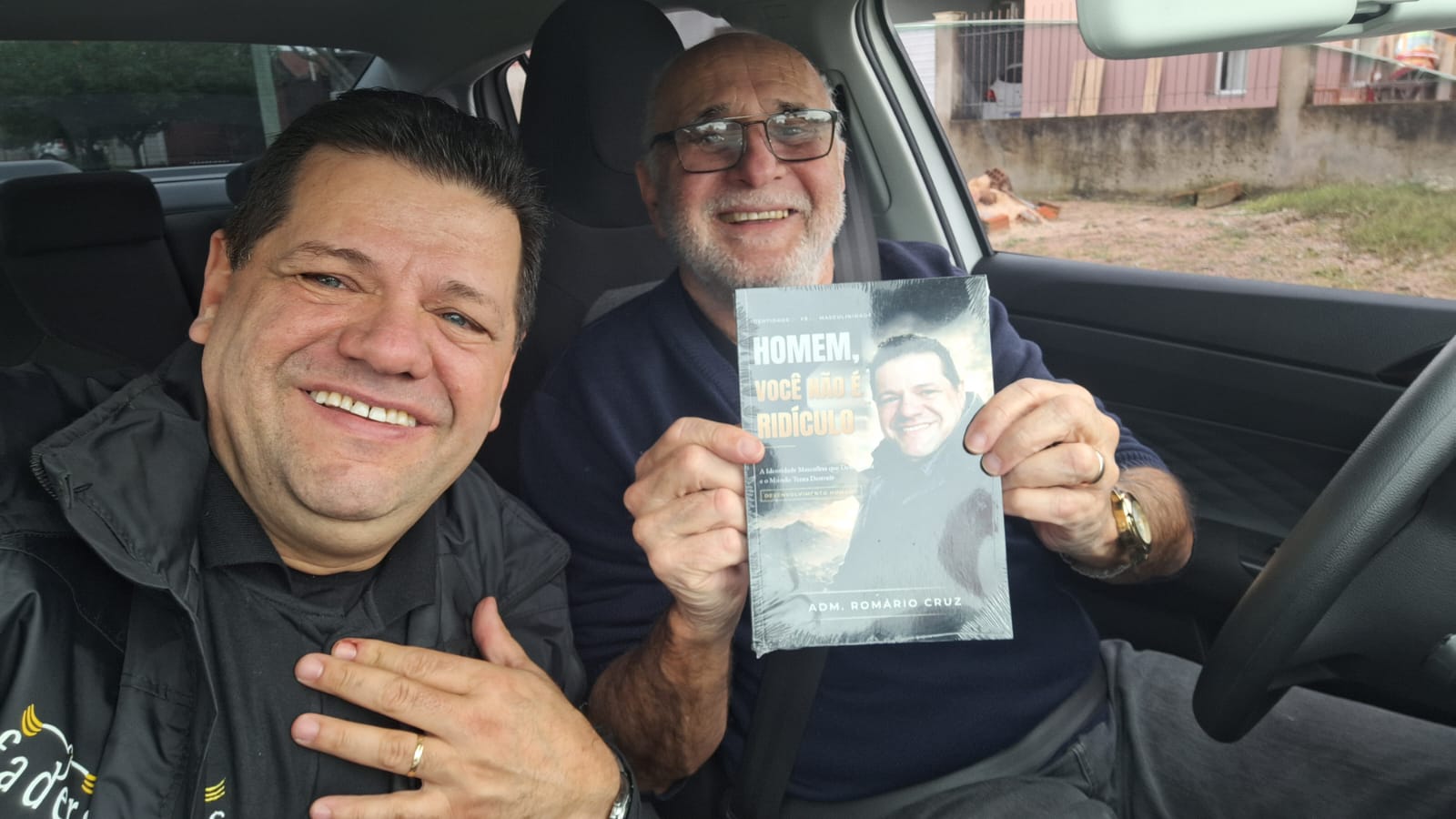 Adm. Romário Cruz com leitor segurando o livro Homem, Você Não É Ridículo