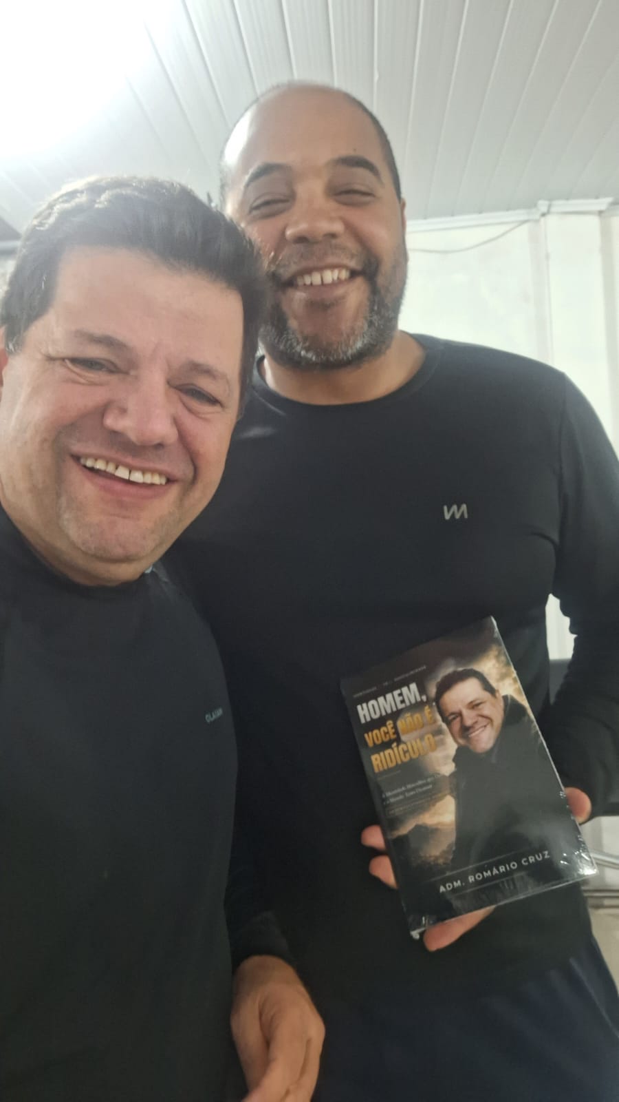 Adm. Romário Cruz com leitor segurando o livro Homem, Você Não É Ridículo