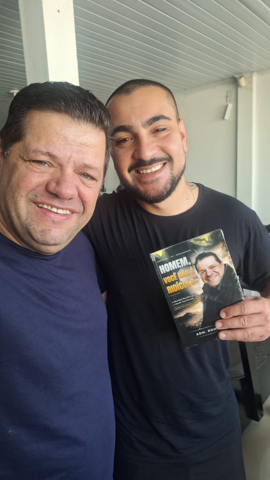 Adm. Romário Cruz com leitor segurando o livro Homem, Você Não É Ridículo