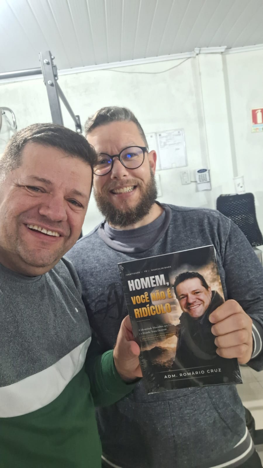 Adm. Romário Cruz com leitor segurando o livro Homem, Você Não É Ridículo