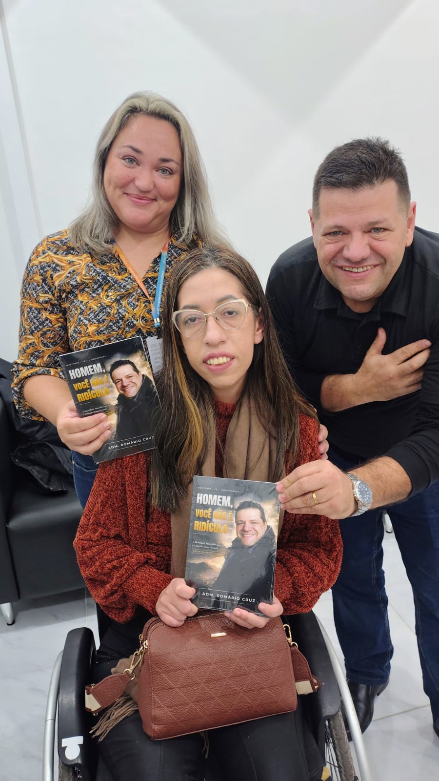 Adm. Romário Cruz com leitoras segurando o livro Homem, Você Não É Ridículo