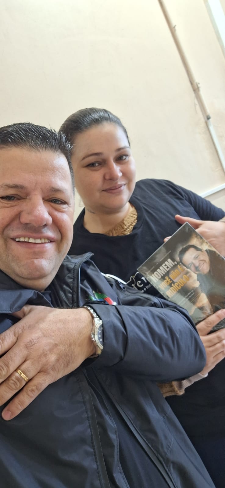 Adm. Romário Cruz abraçado com leitora segurando o livro Homem, Você Não É Ridículo
