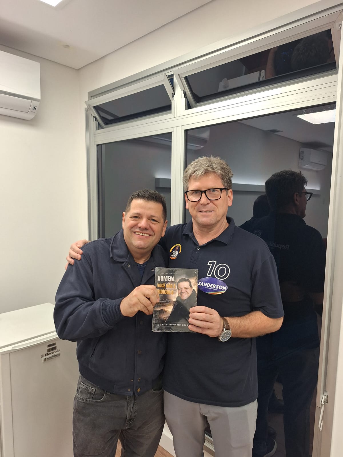 Adm. Romário Cruz com leitor segurando o livro Homem, Você Não É Ridículo
