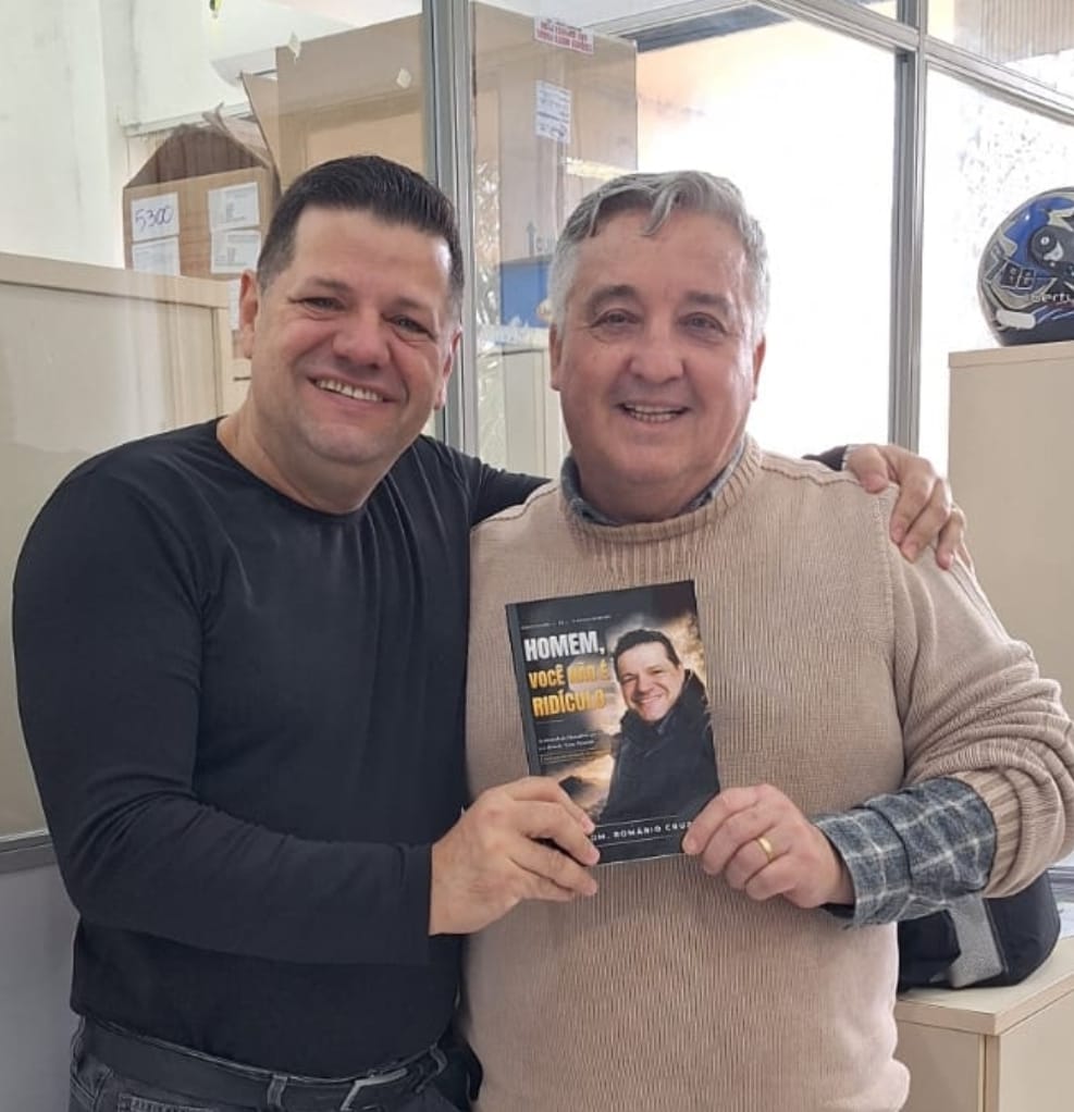 Adm. Romário Cruz com leitor segurando o livro Homem, Você Não É Ridículo