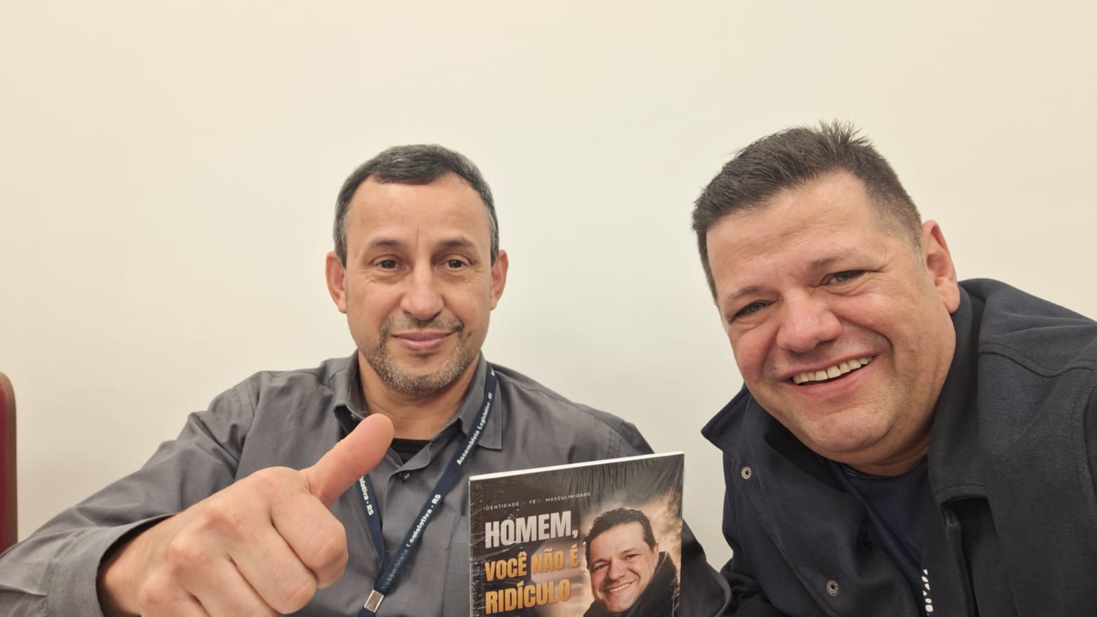 Adm. Romário Cruz com leitor segurando o livro Homem, Você Não É Ridículo