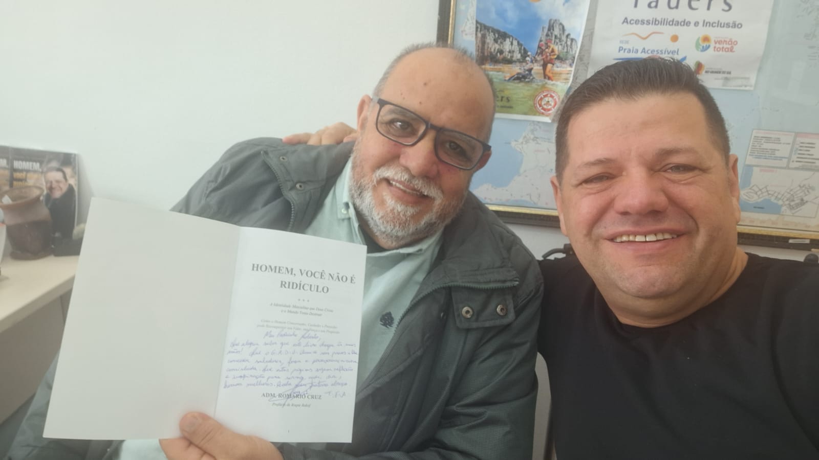 Adm. Romário Cruz com leitor segurando exemplar dedicado do livro Homem, Você Não É Ridículo